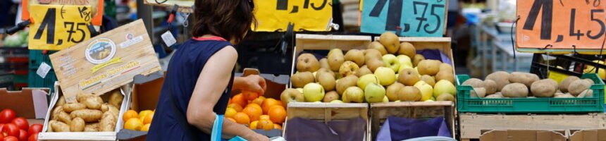 Price tags are seen as a woman shops at a local market in Nice التضخم